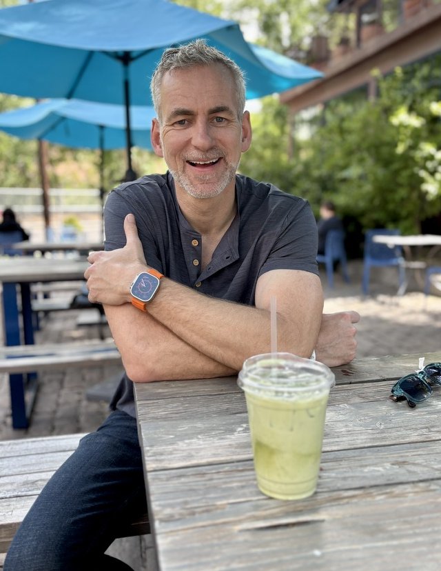 Eelke Folmer smiling at an outdoor cafe table, thumbs up, iced matcha nearby