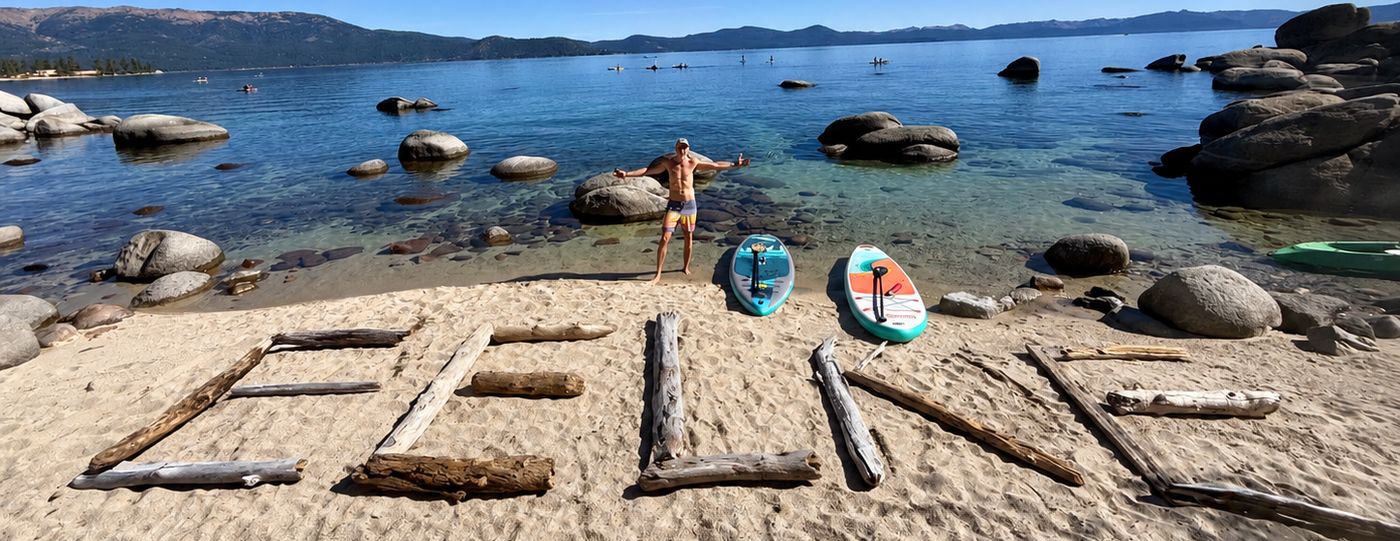 EELKE spelled in driftwood on a Lake Tahoe beach, with two paddleboards and Eelke at the water's edge